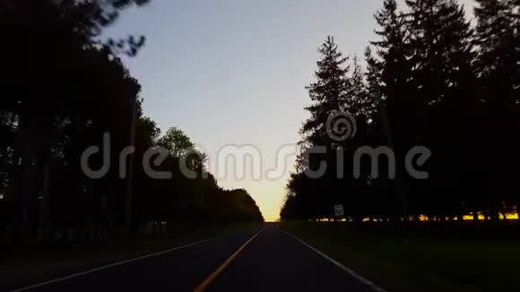 日落时驾驶乡村乡村道路司机视角POV太阳在黄昏时升起在地平线上视频的预览图