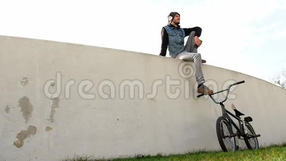 骑着自行车坐在草地上的年轻人坐在灯光下听音乐视频的预览图