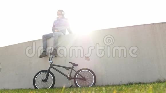 骑着自行车坐在草地上的年轻人坐在灯光下听音乐视频的预览图