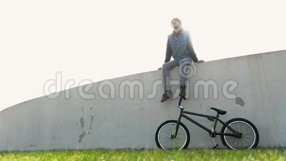 骑自行车坐在草地上的年轻人坐在灯光下视频的预览图