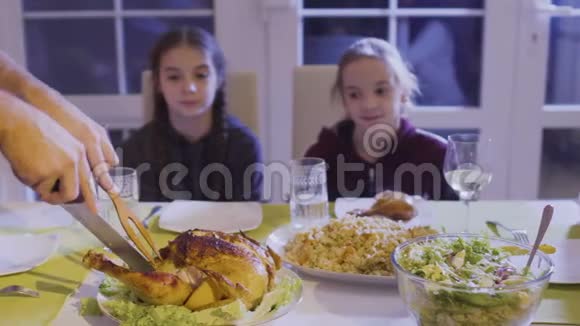 男人在喜庆的餐桌上切鸡把鸡腿放在女儿盘子里视频的预览图