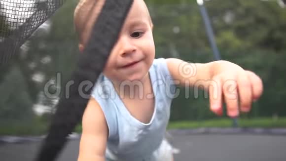 微笑的婴儿在公园的蹦床上慢悠悠地运动视频的预览图