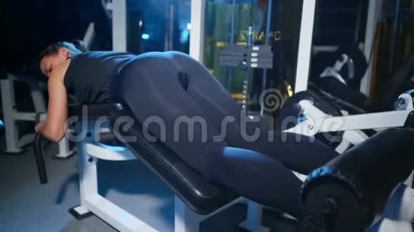 躺在模拟器里的女孩对大腿后部的肌肉进行锻炼二头肌臀部运动型妇女视频的预览图