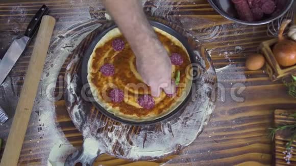 比萨列罗烹饪比萨饼与香肠意大利香肠在木制桌子顶部的视图意大利厨师做比萨饼视频的预览图