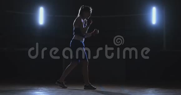 训练一个漂亮的女拳击手在黑暗的房间里打拳斯坦迪卡姆自卫和战斗准备视频的预览图