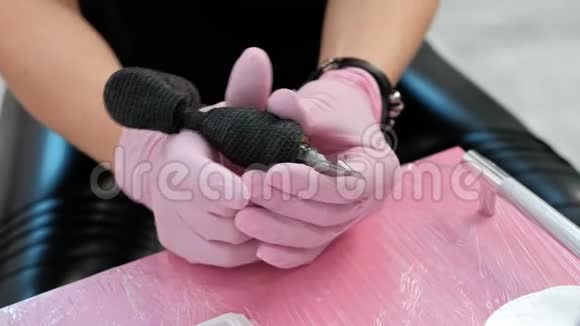 纹身师傅在纹身机上插针红色背景上的粉红色安全手套视频的预览图