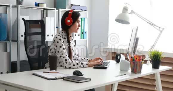 女商人戴着红色耳机听音乐和使用笔记本电脑视频的预览图