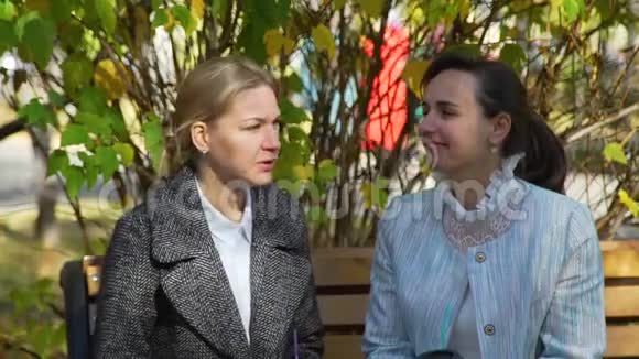 两个迷人的女人在秋天的公园里交谈视频的预览图
