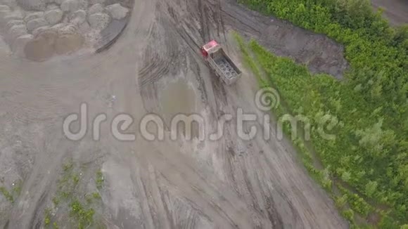 在一个有沙面和乡村道路的建筑工地上一辆尖头卡车驶往装载沙子和土壤的高空俯视图视频的预览图
