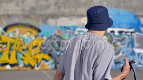 一个带背包的成年男子朝一面涂鸦墙的后景视频的预览图