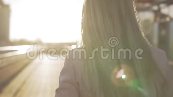 美丽的金发女郎对着镜头微笑日落时转身视频的预览图