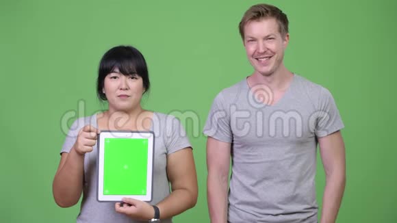 年轻快乐的多民族夫妇一起展示数字平板电脑并竖起大拇指视频的预览图