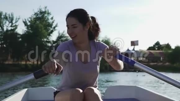 美丽的女孩笑着在船上划桨视频的预览图