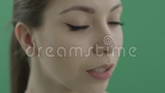 漂亮的年轻女人猫眼咬着她的嘴唇紧贴着绿色的背景视频的预览图