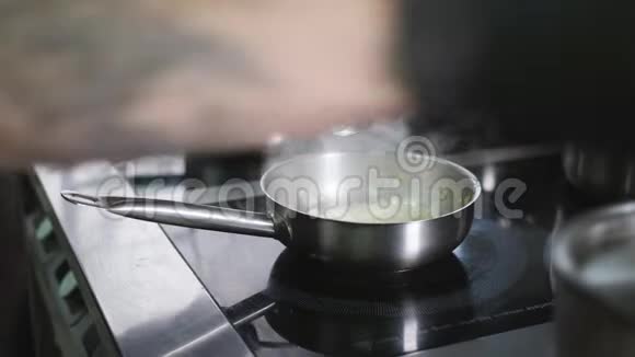 厨师用雄手在平底锅中搅拌切碎的洋葱然后用植物油煎炸视频的预览图