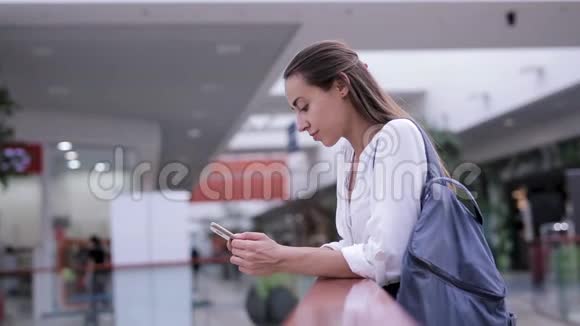 美丽的微笑的女人在商场里接到一个手机的来电视频的预览图