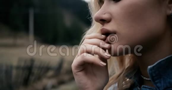 一个时髦的年轻女孩戴着帽子在日落时摆姿势的肖像用手指在嘴唇上玩4k视频的预览图