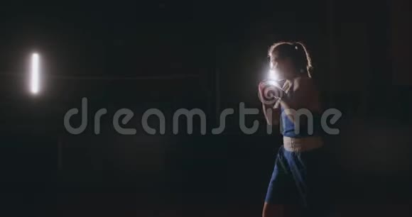 训练一个漂亮的女拳击手在黑暗的房间里打拳斯坦迪卡姆自卫和战斗准备视频的预览图