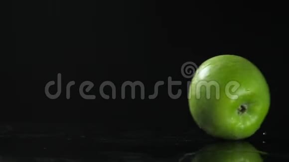 黑桌上的绿湿苹果水果在两边翻滚在桌子上翻滚黑色背景视频的预览图
