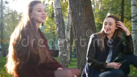 秋天公园里的漂亮女孩坐在毯子上聊天视频的预览图