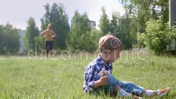 一个可爱的小男孩坐在草地上视频的预览图