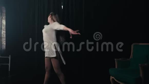 年轻漂亮的女孩在一个带绿色椅子的黑暗房间里跳舞视频的预览图