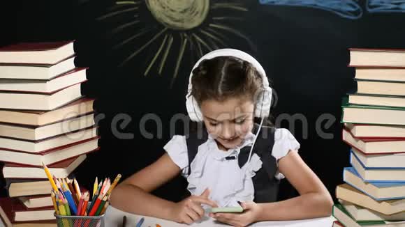 现代学校观念漂亮的女孩坐在一张桌子上手里拿着一堆书她孩子后面的黑板正在学习视频的预览图