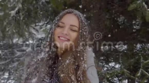 雪花落在美丽的女孩的脸和长发在缓慢的运动白雪皑皑的年轻美女画像视频的预览图
