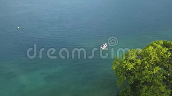 鸟瞰小摩托艇漂浮在绿松石海水中靠近大绿树行动避暑胜地视频的预览图