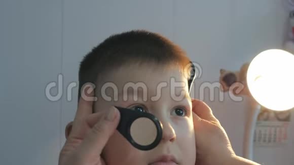 在眼科诊所的孩子用放大镜检查儿童眼底视频的预览图