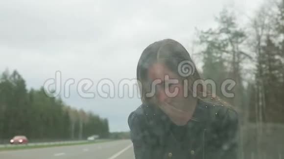 年轻的棕色头发的女人打开了一辆破车的引擎盖视频的预览图