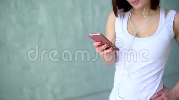 这位年轻健康的女孩在健身房的耳机里听音乐的肖像视频的预览图