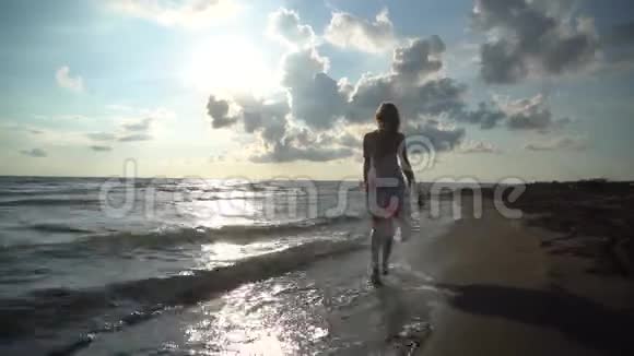 穿裙子的女人在海滩上散步视频的预览图