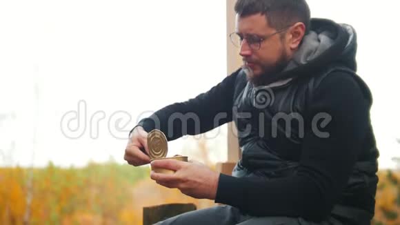 一个人坐在高空平台上用刀吃罐头食品视频的预览图