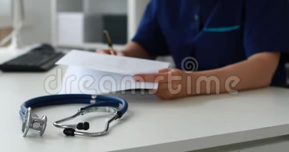 听诊器在桌子上的裁剪图像在前台后面的医生填写文件视频的预览图