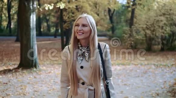秋天美丽的金发女郎走在公园里微笑着视频的预览图