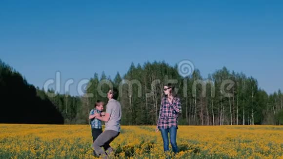 爸爸把儿子扔到空中妈妈站在旁边一家人走在田野上在森林附近开着黄花视频的预览图
