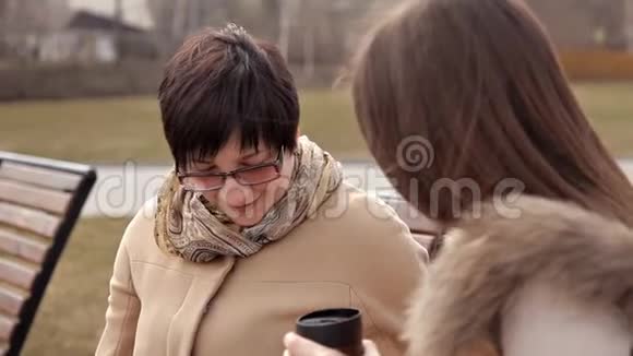 快乐的高年级母女坐在公园的长椅上聊天视频的预览图