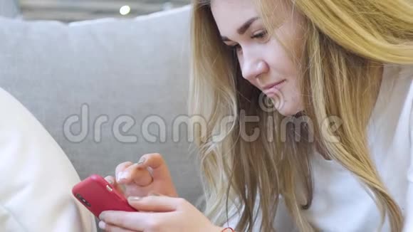 美丽的金发女郎手里拿着一个电话聊天上网微笑着视频的预览图