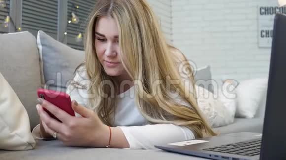 穿着睡衣的漂亮年轻女人手里拿着智能手机一边在屏幕上打字一边在活人面前聊天视频的预览图