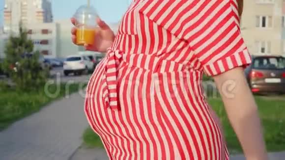 等待孩子的孕妇女人拿着一杯果汁在城市里散步温柔的概念视频的预览图
