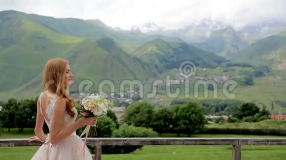 美丽的新娘欣赏美丽的山景和一束鲜花婚礼日视频的预览图