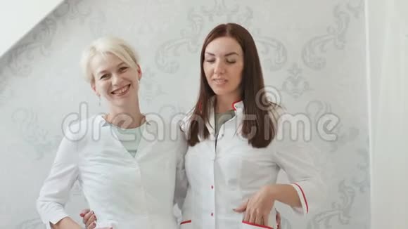 两个微笑的女人穿着白色外套的金发女郎年轻的专家是美容师视频的预览图