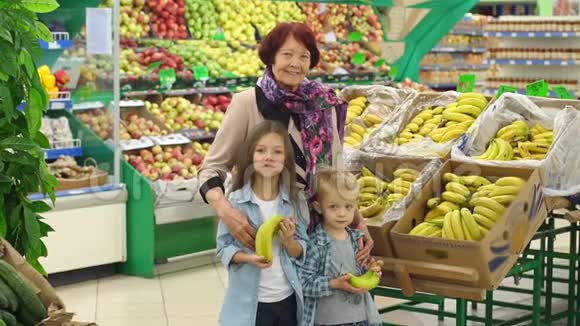 快乐的老妇人带着孙子在超市买水果肖像视频的预览图