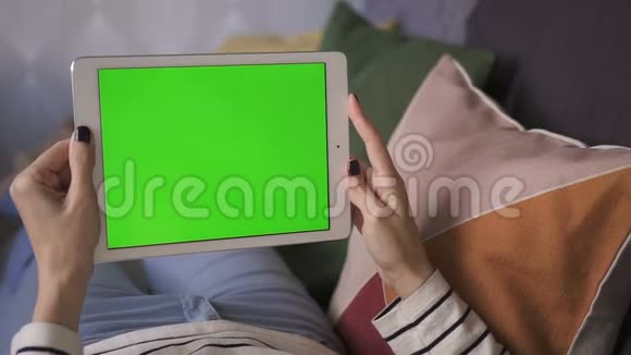 商务数码亚洲女性手持绿色屏幕平板电脑在家中的沙发上视频的预览图