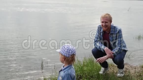 一个人和他的儿子在湖边散步爸爸和他的儿子在河边散步一个人蹲在他儿子面前视频的预览图