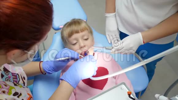 生病的孩子在口腔科医生检查时张开嘴躺在牙椅上手里拿着工具放在牙科的柜子里视频的预览图