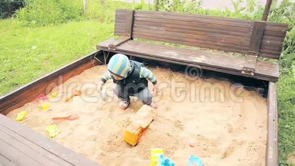 幼儿园里的一个孩子在沙坑里玩耍视频的预览图