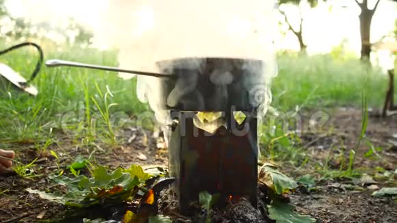在森林里露营炉子上烧着一壶食物烟来自火视频的预览图