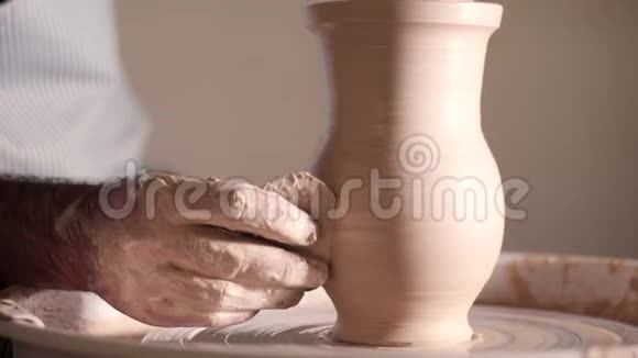 经验丰富的陶工用陶制工具塑造陶罐紧紧抓住在陶工车轮上工作的男性双手视频的预览图